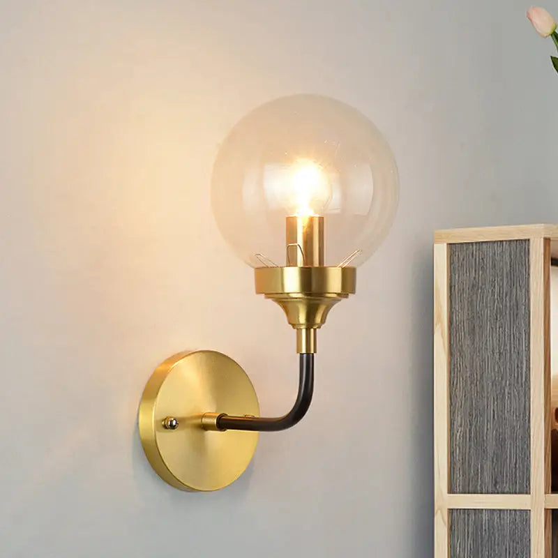 Modern brass curved arm wall sconce with clear glass for bedroom
