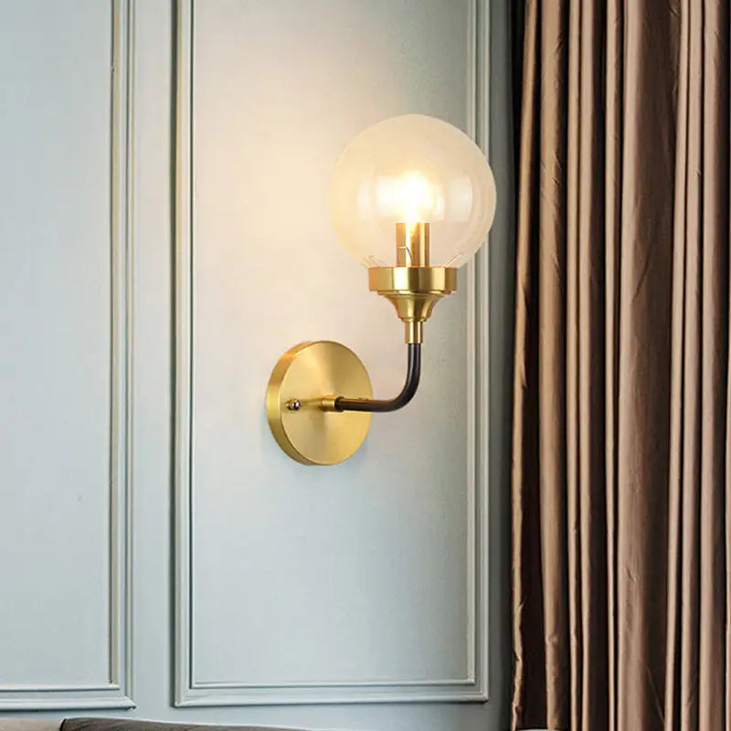 Modern brass curved arm wall sconce with clear glass for bedroom