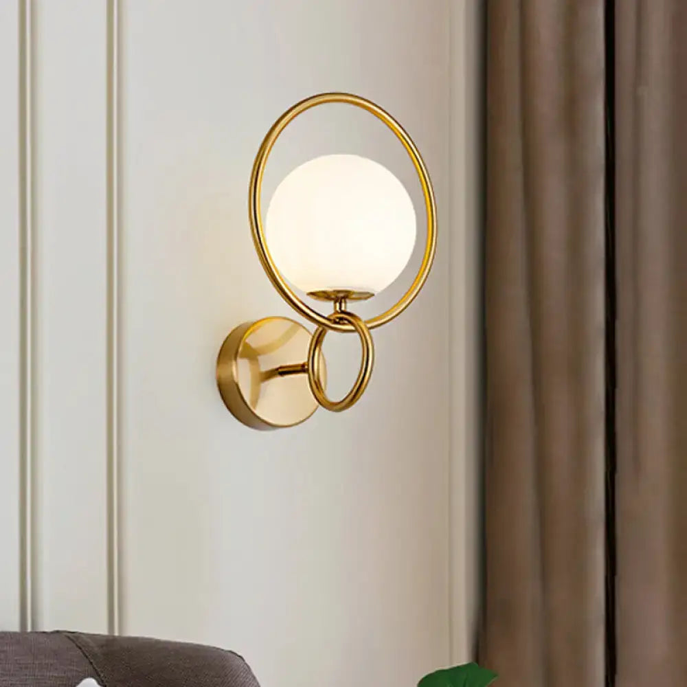 Modernist gold wall sconce with white glass shade for bedroom
