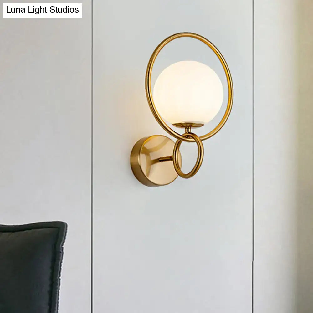 Modernist gold wall sconce with white glass shade for bedroom